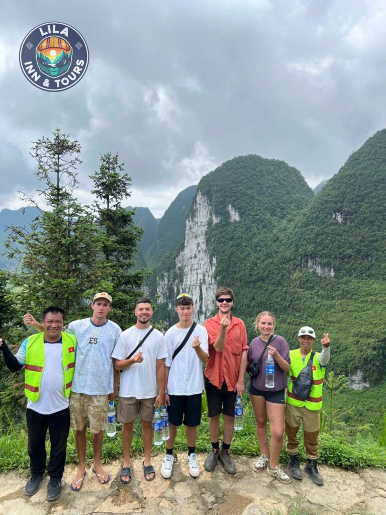 A group of adventurers posing in front of a majestic Ha Giang mountain range.