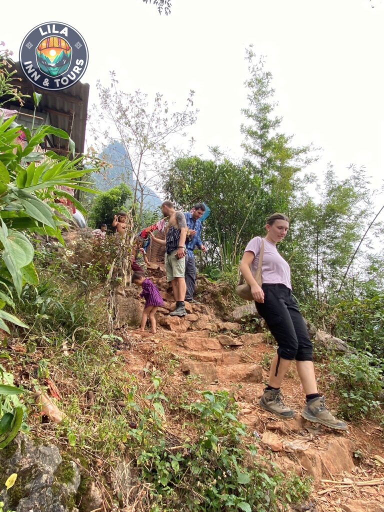 A traveler trekking through a remote village in Ha Giang, surrounded by lush greenery and scenic mountain paths.